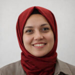 A woman wearing a burgundy coloured türban and a olive green collared shirt